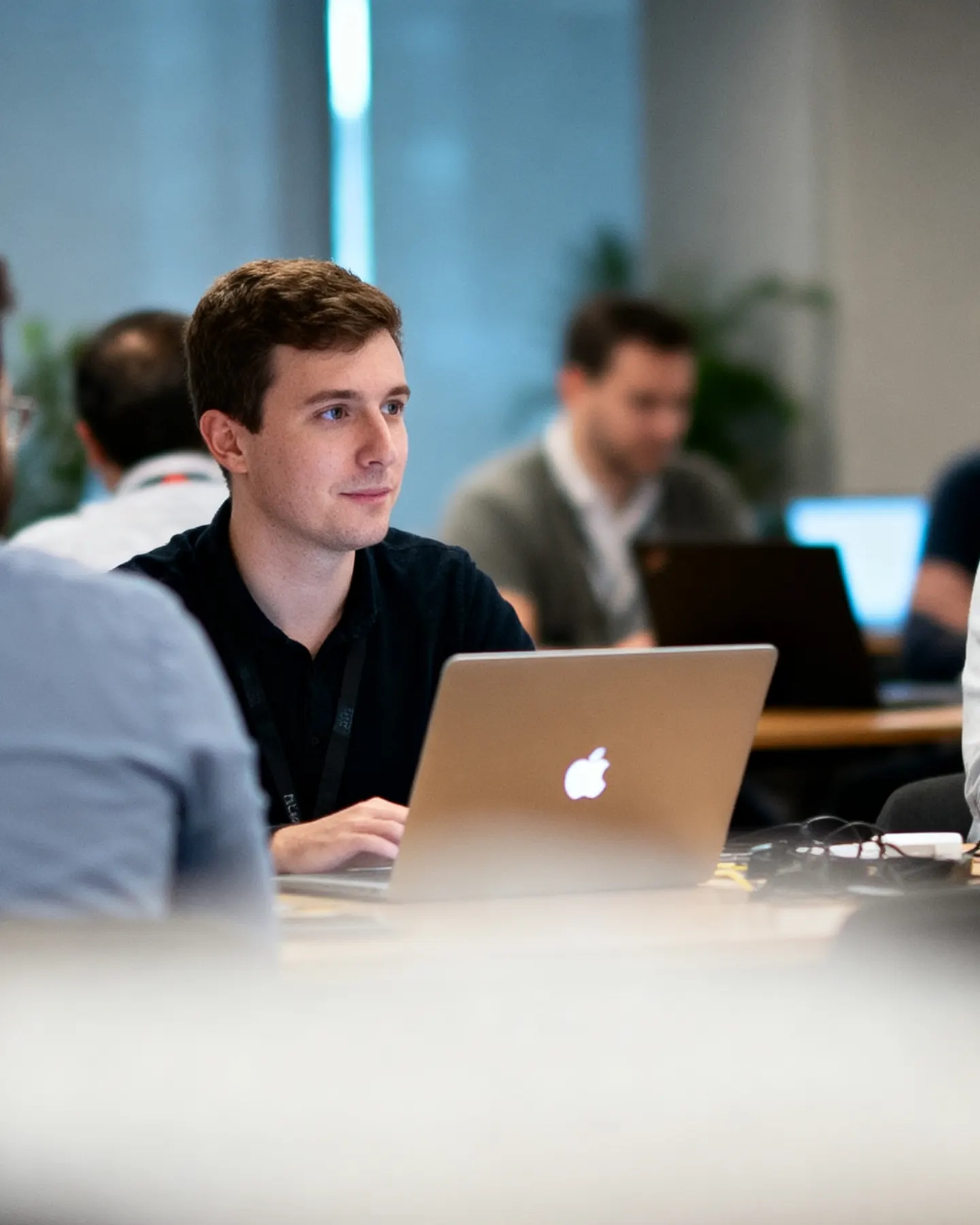 An engineer at work on a laptop, in a busy open-plan office