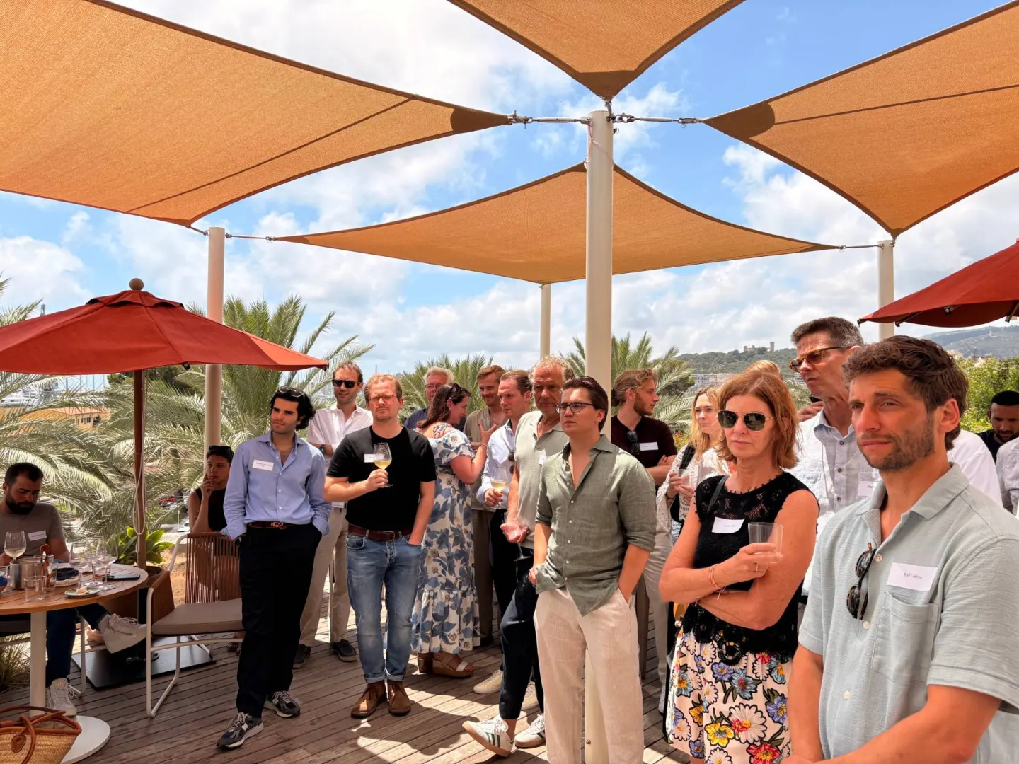 A partner talk on a rooftop terrace under sun sails